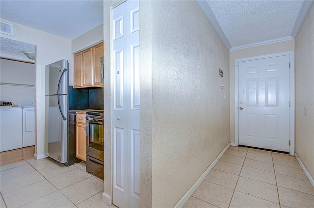 kitchen featuring washer and dryer, light tile patterned floors, stainless steel appliances, and a textured ceiling