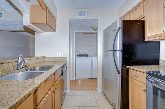 kitchen with washing machine and clothes dryer, light tile patterned floors, light brown cabinetry, and sink