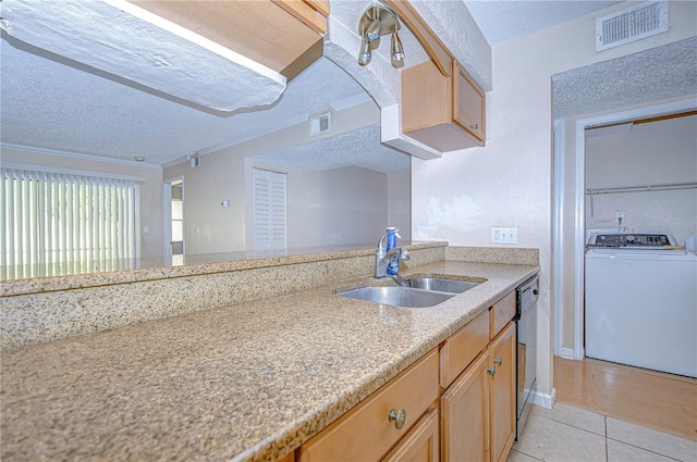 kitchen with a textured ceiling, light wood-type flooring, sink, and washer / clothes dryer