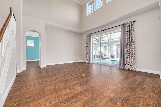 spare room with a high ceiling, dark hardwood / wood-style floors, and ornamental molding