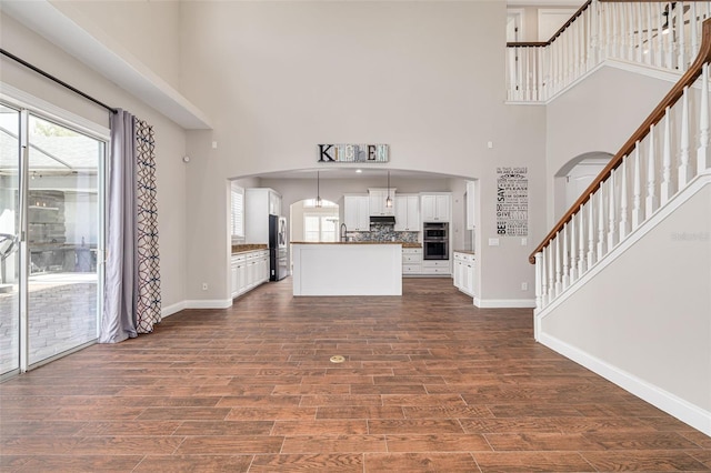 unfurnished living room with a towering ceiling, dark wood-type flooring, and sink