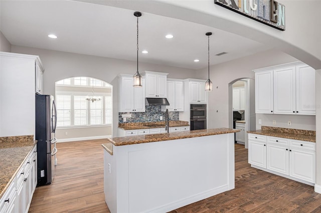 kitchen with dark hardwood / wood-style flooring, stainless steel appliances, white cabinets, a center island, and hanging light fixtures