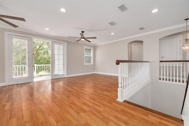 empty room with ceiling fan with notable chandelier, light hardwood / wood-style floors, and crown molding