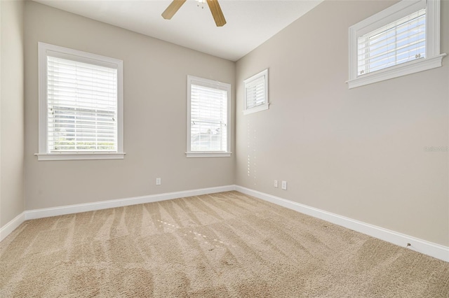 carpeted empty room with ceiling fan and a wealth of natural light