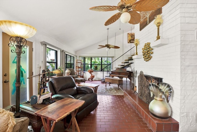 interior space featuring brick floor, a fireplace, ceiling fan, and high vaulted ceiling