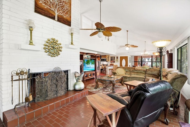 living room featuring a towering ceiling, brick floor, a fireplace, and ceiling fan with notable chandelier