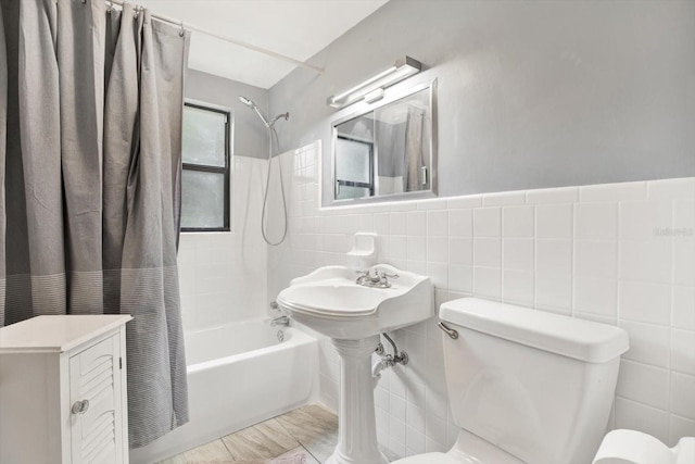 full bath with toilet, tile walls, and shower / tub combo with curtain