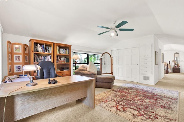 office area with visible vents, vaulted ceiling, a ceiling fan, and light colored carpet