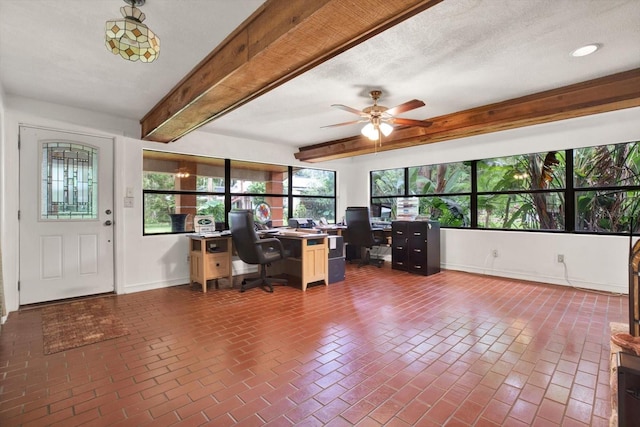 unfurnished office with brick floor, a textured ceiling, baseboards, and beam ceiling