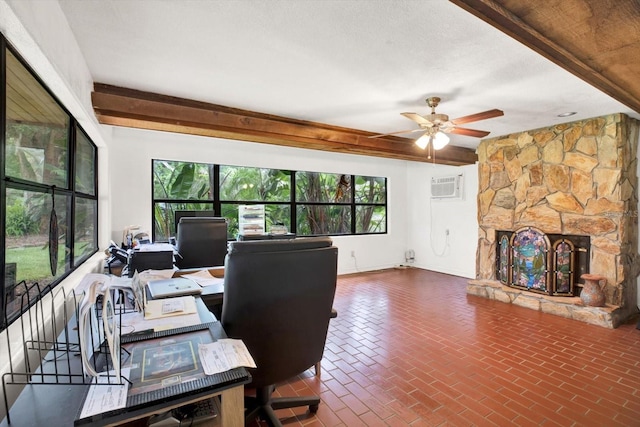 office area featuring a stone fireplace, brick floor, a ceiling fan, beamed ceiling, and a wall mounted air conditioner