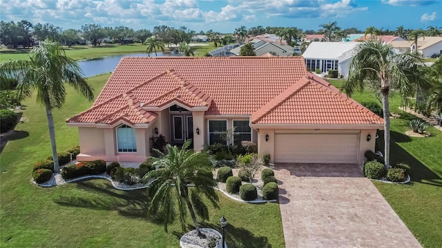 mediterranean / spanish home with a water view, a front yard, and a garage