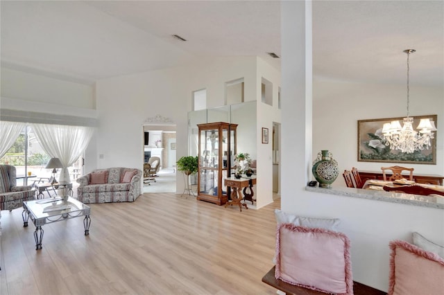 living room with hardwood / wood-style floors, high vaulted ceiling, and an inviting chandelier