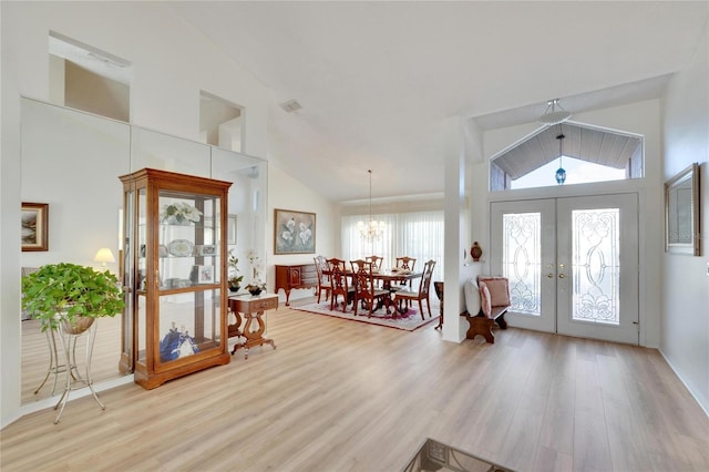 foyer with french doors, light hardwood / wood-style floors, plenty of natural light, and a notable chandelier