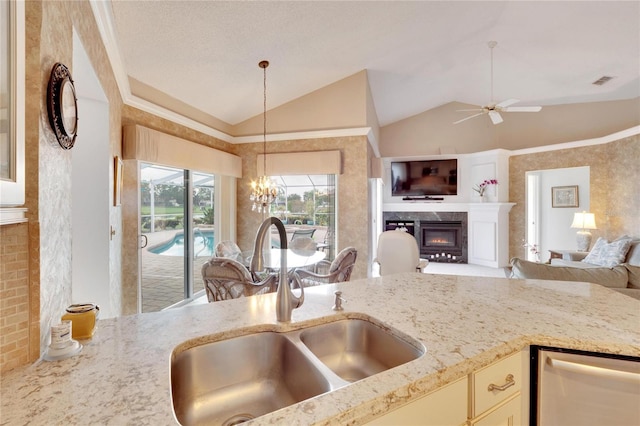 kitchen with a fireplace, ceiling fan with notable chandelier, lofted ceiling, and sink