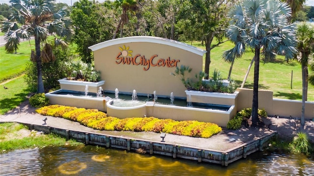 community sign featuring a water view and a yard