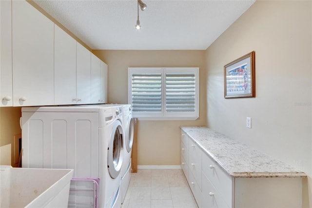 clothes washing area featuring cabinets, a textured ceiling, sink, light tile patterned floors, and washing machine and dryer