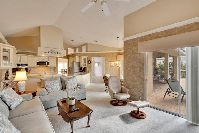 carpeted living room with high vaulted ceiling and ceiling fan with notable chandelier