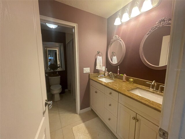 bathroom with toilet, vanity, a textured ceiling, and tile patterned floors