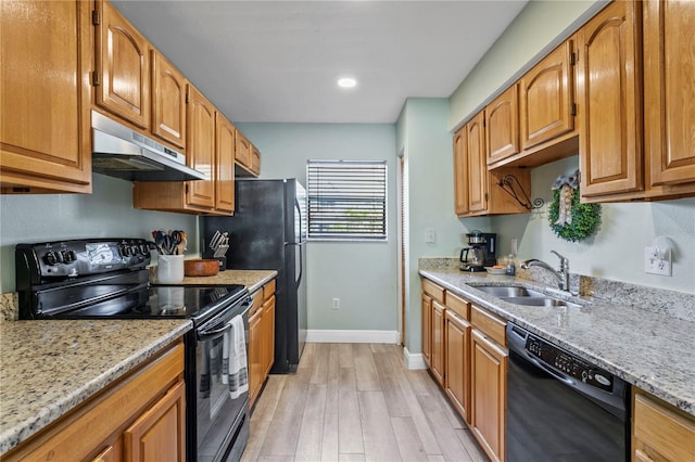 kitchen with light stone counters, light wood-type flooring, sink, and black appliances