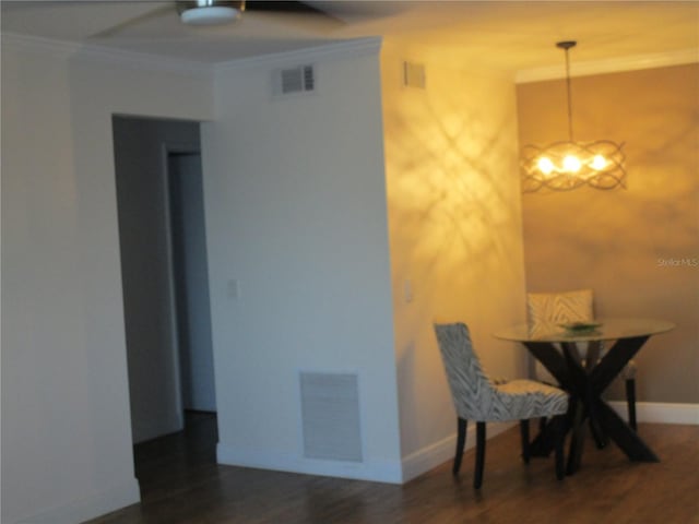 dining area with dark hardwood / wood-style floors, ornamental molding, and an inviting chandelier