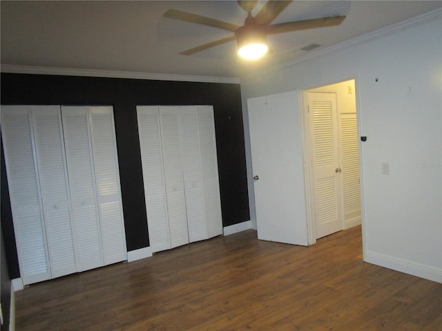 unfurnished bedroom with two closets, ceiling fan, crown molding, and dark hardwood / wood-style floors