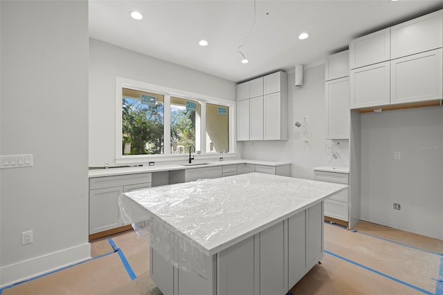 kitchen featuring tasteful backsplash, light stone countertops, sink, white cabinets, and a center island