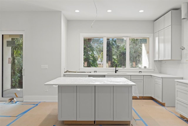 kitchen featuring light stone counters, sink, and a center island