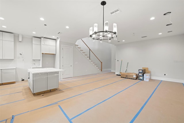 kitchen featuring white cabinetry, an inviting chandelier, decorative light fixtures, and a center island