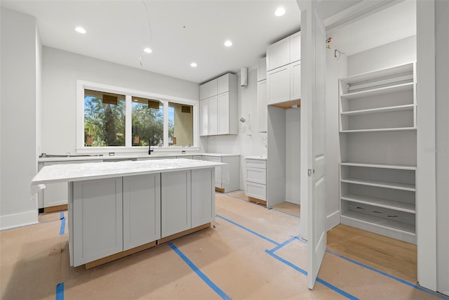 kitchen with white cabinetry, sink, and a center island