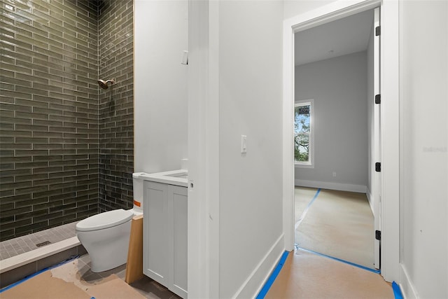 bathroom with vanity, toilet, and a tile shower