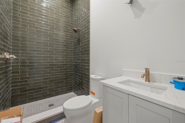 bathroom with vanity, toilet, and a tile shower