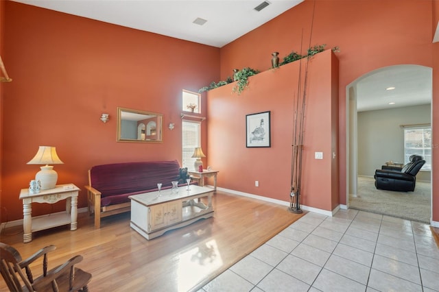 living room with a towering ceiling and light hardwood / wood-style flooring