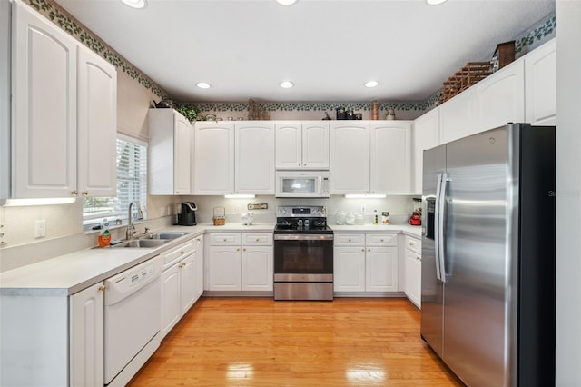 kitchen featuring white cabinets, appliances with stainless steel finishes, light wood-type flooring, and sink