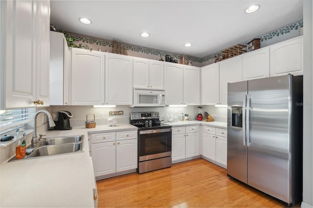 kitchen featuring white cabinets, appliances with stainless steel finishes, light wood-type flooring, and sink