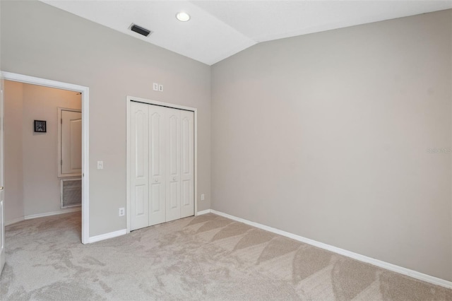 unfurnished bedroom featuring a closet, lofted ceiling, and light carpet