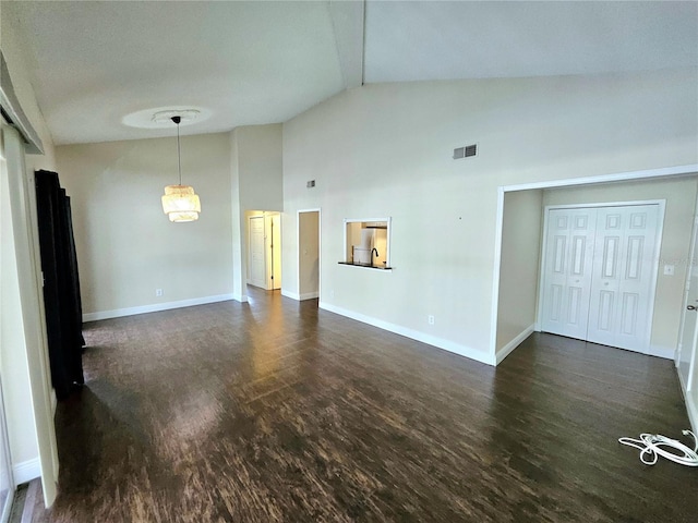 spare room featuring high vaulted ceiling and dark wood-type flooring