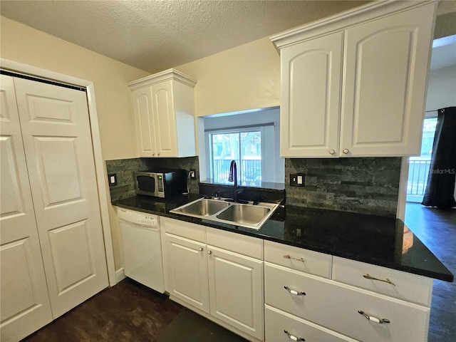 kitchen featuring white dishwasher, a textured ceiling, tasteful backsplash, sink, and white cabinetry