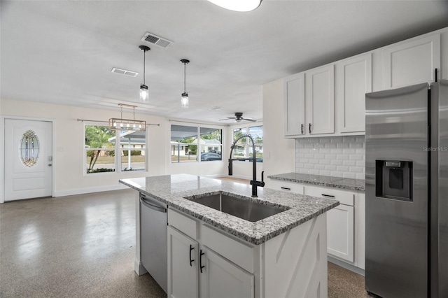 kitchen with pendant lighting, sink, appliances with stainless steel finishes, light stone countertops, and white cabinets