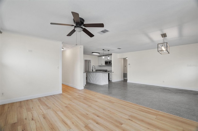 unfurnished living room with ceiling fan, sink, and light hardwood / wood-style floors