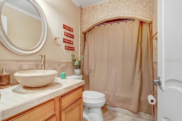 bathroom with vanity, crown molding, tile patterned flooring, toilet, and tile walls