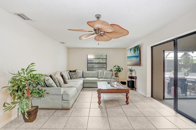 living room featuring ceiling fan, light tile patterned flooring, and a textured ceiling