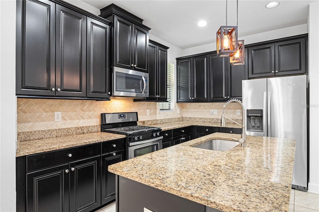 kitchen featuring sink, tasteful backsplash, an island with sink, decorative light fixtures, and appliances with stainless steel finishes