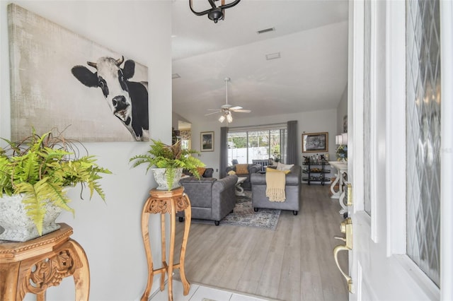 living room with ceiling fan, light wood-type flooring, and lofted ceiling