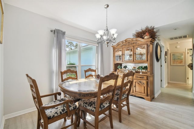 dining room with light hardwood / wood-style flooring and a notable chandelier