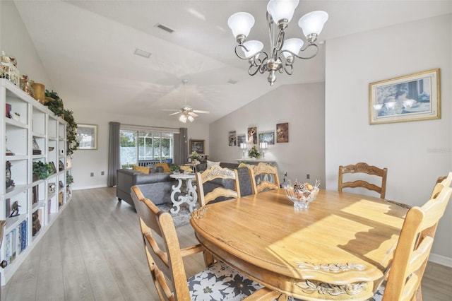 dining area with ceiling fan with notable chandelier, vaulted ceiling, and light hardwood / wood-style flooring