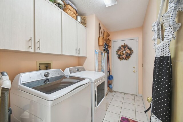 washroom with cabinets, independent washer and dryer, a textured ceiling, and light tile patterned floors