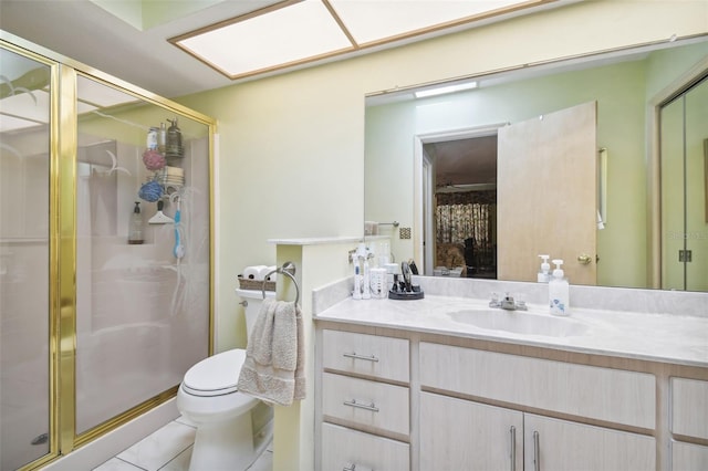 bathroom with tile patterned floors, vanity, a shower with shower door, and toilet