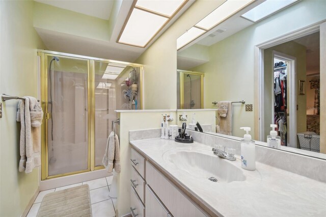 bathroom featuring a skylight, tile patterned flooring, vanity, and a shower with door