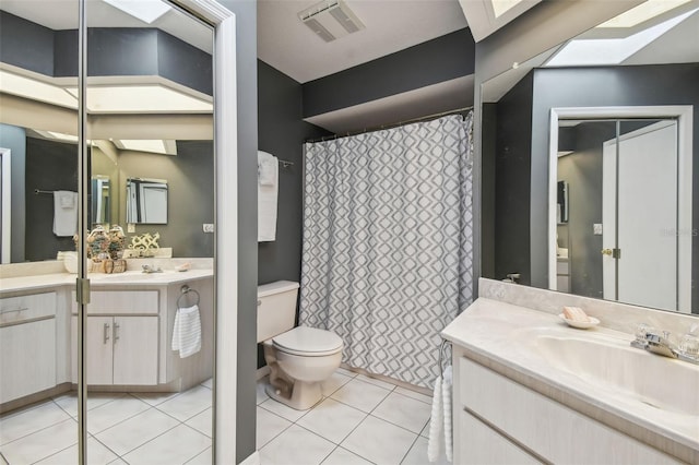 bathroom featuring tile patterned floors, a skylight, vanity, and toilet