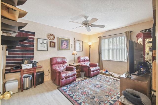 living room featuring a textured ceiling, light hardwood / wood-style floors, and ceiling fan